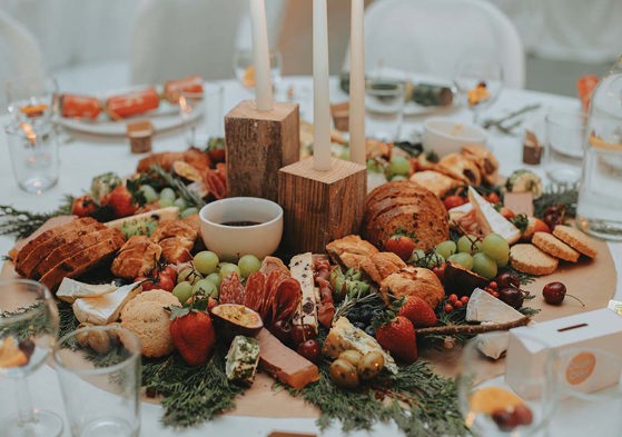 display of meats, cheeses, bread and fruit in the middle of a round table for guests to share 